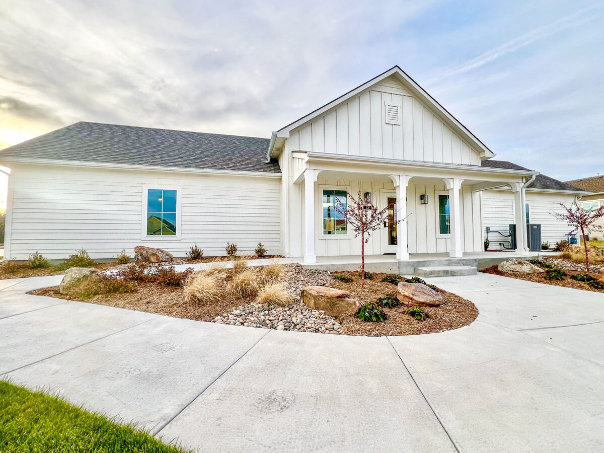 front of white home with beautifully landscaped yard and driveway